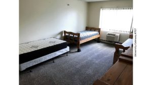 Carpeted bedroom with three beds, two dressers, AC unit, and window