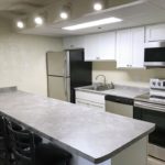 Kitchen with white cabinets, light gray countertops, barstool seating, and stainless steel appliances