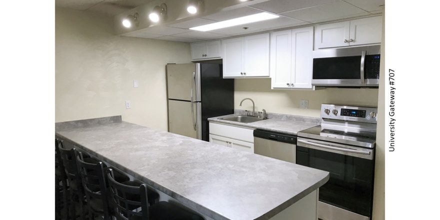 Kitchen with white cabinets, light gray countertops, barstool seating, and stainless steel appliances