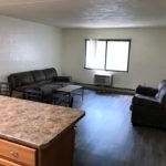 Living room with LVT flooring, end table, coffee table, window, AC unit, loveseat, and sofa