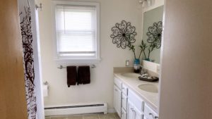 Bathroom with double sink vanity, mirror, and tub/shower combo