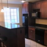 Basement bar area with bar stool seating, dishwasher, fridge, and microwave