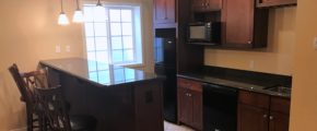 Basement bar area with bar stool seating, dishwasher, fridge, and microwave