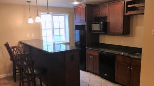 Basement bar area with bar stool seating, dishwasher, fridge, and microwave