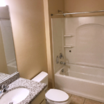 Bathroom with shower/tub combo, toilet, mirror and vanity.