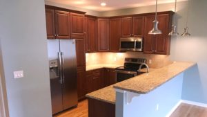 Kitchen with dark wood cabinets, wood-style flooring, stainless steel appliances, stone countertops