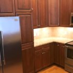 Kitchen with dark wood cabinets, wood-style flooring, stainless steel appliances, stone countertops