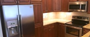 Kitchen with dark wood cabinets, wood-style flooring, stainless steel appliances, stone countertops