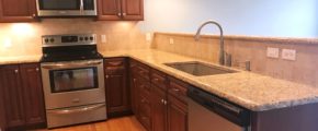 Kitchen with dark wood cabinets, wood-style flooring, stainless steel appliances, stone countertops