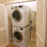 Laundry closet with stacked washer and dryer and wire shelving