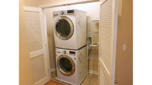 Laundry closet with stacked washer and dryer and wire shelving