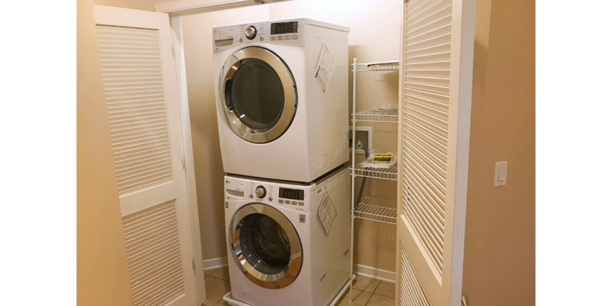 Laundry closet with stacked washer and dryer and wire shelving