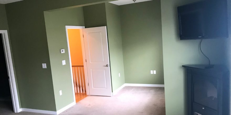 Unfurnished, carpeted owner's suite bedroom with ceiling fan, TV, and fireplace