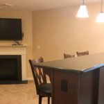 Carpeted basement with fireplace, TV, bar counter and bar seating