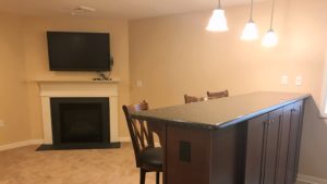 Carpeted basement with fireplace, TV, bar counter and bar seating