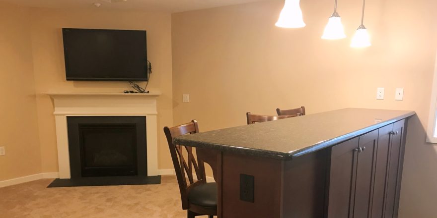 Carpeted basement with fireplace, TV, bar counter and bar seating