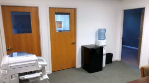 Office space with copy machine, small fridge, and water cooler