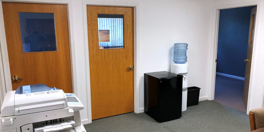 Office space with copy machine, small fridge, and water cooler