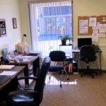 Office with three desks, chairs, a closet, and large window
