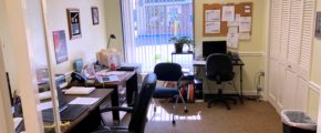 Office with three desks, chairs, a closet, and large window