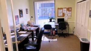 Office with three desks, chairs, a closet, and large window