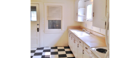 Kitchen with tile floors, white cabinets, and white appliances