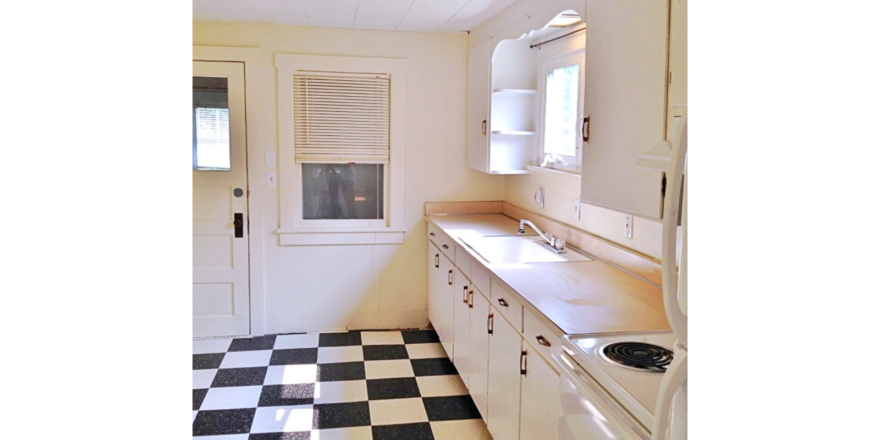 Kitchen with tile floors, white cabinets, and white appliances