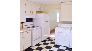 Kitchen with tile floors, white cabinets, and white appliances