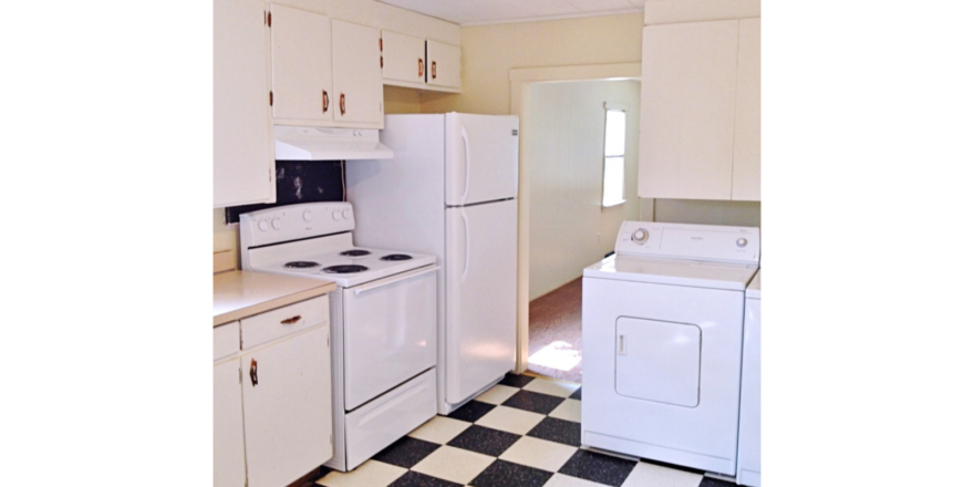Kitchen with tile floors, white cabinets, and white appliances