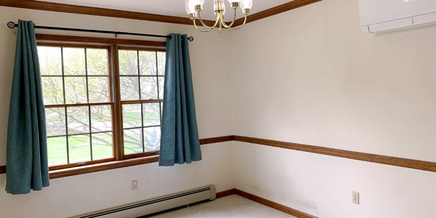 Carpeted dining area with window and chandelier
