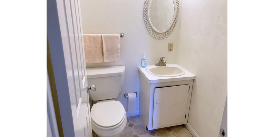 Half bathroom with toilet, vanity, and mirror
