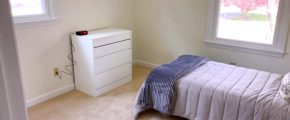 Carpeted bedroom with twin bed, dresser, windows, and clock