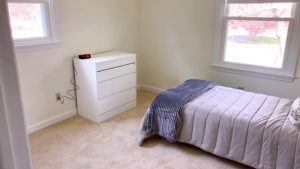 Carpeted bedroom with twin bed, dresser, windows, and clock