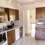 Kitchen with wood-tone cabinets, white appliances, track lighting, and ceramic tile flooring