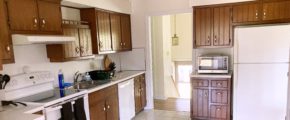 Kitchen with wood-tone cabinets, white appliances, track lighting, and ceramic tile flooring