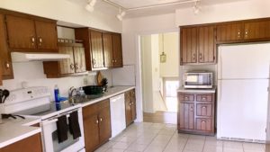 Kitchen with wood-tone cabinets, white appliances, track lighting, and ceramic tile flooring