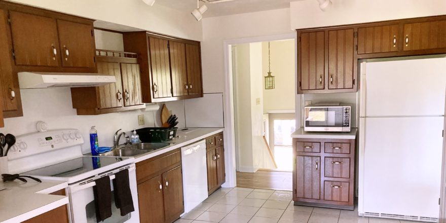 Kitchen with wood-tone cabinets, white appliances, track lighting, and ceramic tile flooring