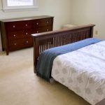 Carpeted bedroom with bed and dresser