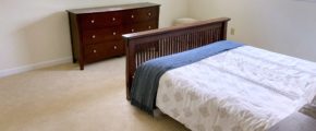 Carpeted bedroom with bed and dresser