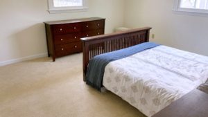 Carpeted bedroom with bed and dresser