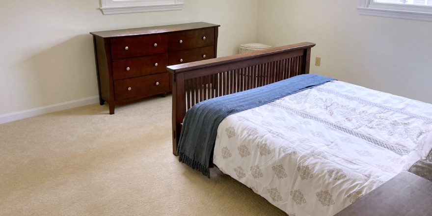 Carpeted bedroom with bed and dresser