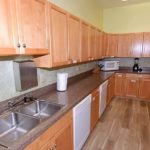 U-Shaped kitchen with wood-tone cabinets, white appliances, and double-sink