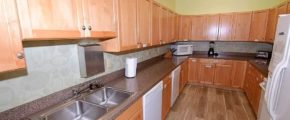 U-Shaped kitchen with wood-tone cabinets, white appliances, and double-sink