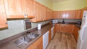 U-Shaped kitchen with wood-tone cabinets, white appliances, and double-sink