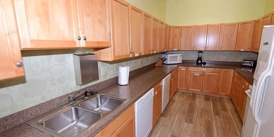 U-Shaped kitchen with wood-tone cabinets, white appliances, and double-sink