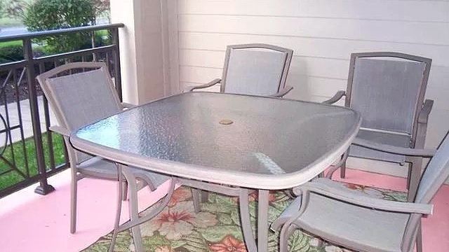 Balcony with railing, patio table and chairs, and rug