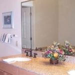 Bathroom with double sink vanity, large mirror, and flower basket