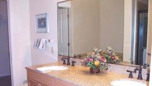Bathroom with double sink vanity, large mirror, and flower basket