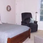 Bedroom with arm chairs, large bed, and storage cabinet