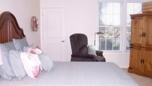 Bedroom with large bed, chair, and storage cabinet